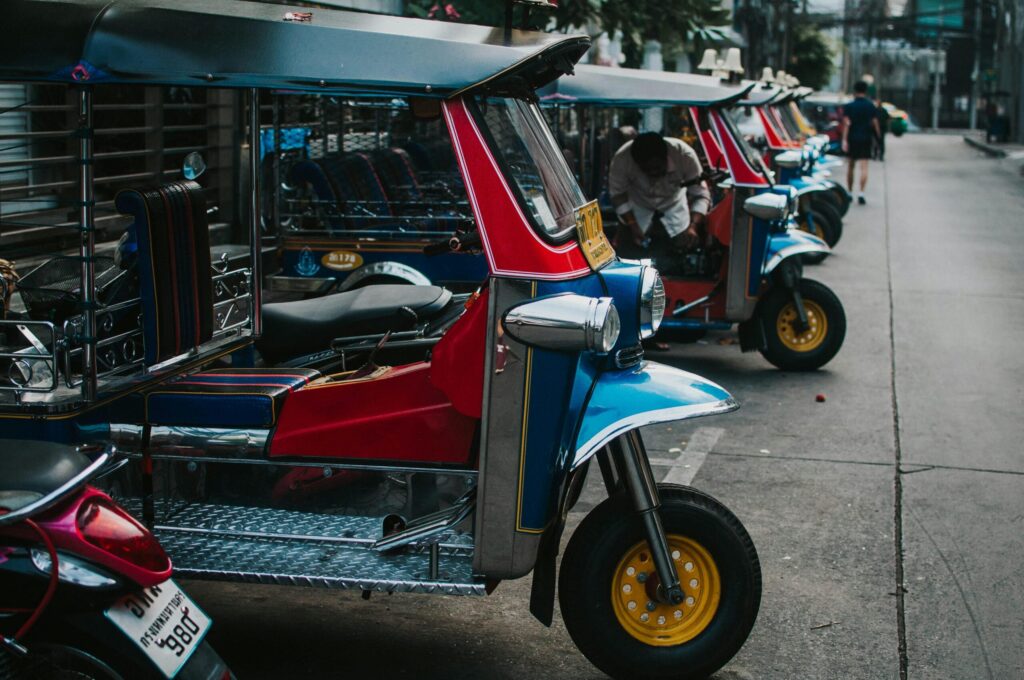 Colorful tuk tuks parked in a row on an urban street, emphasizing transportation culture.